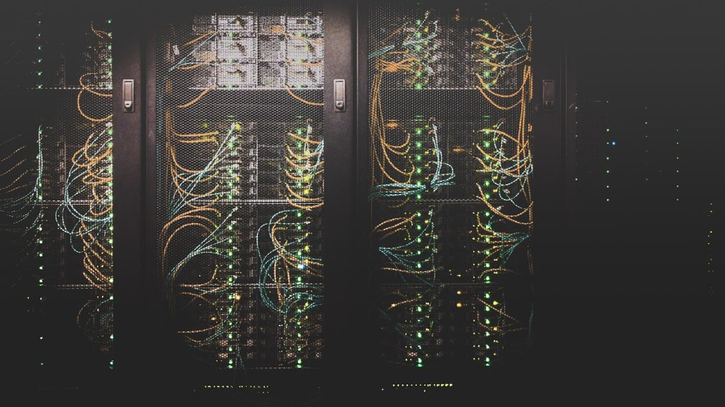 Rows of dark server cabinets with status lights and dressed fibre patch cabling.