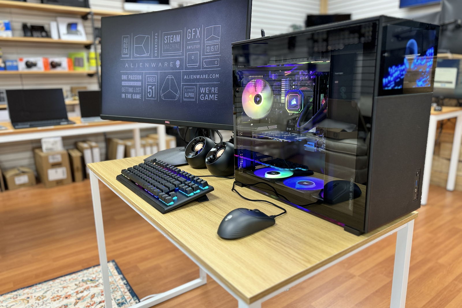 A custom built desktop with a glass side panel, liquid cooling and lit fans, next to a curved monitor on a display table in the Express IT store.