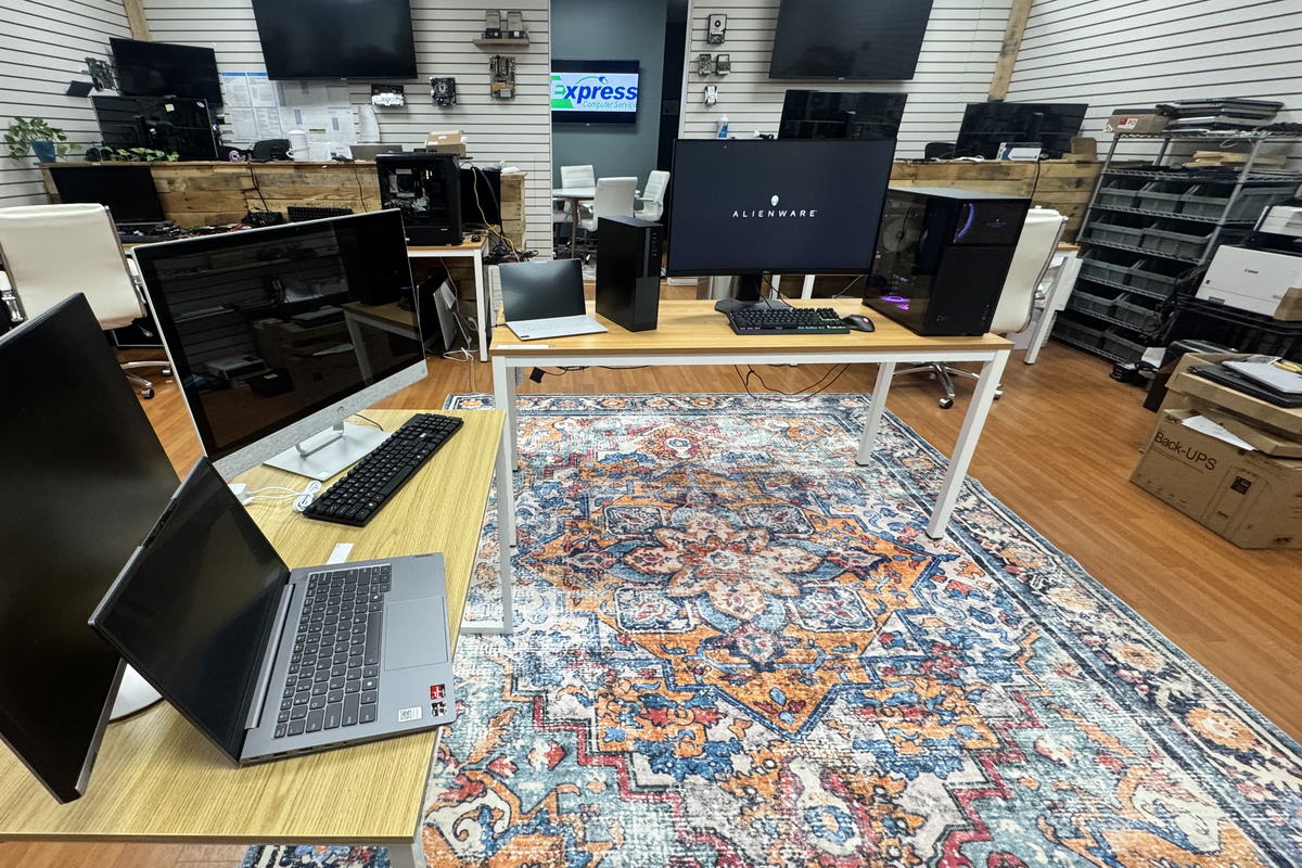 The Express IT Solutions showroom floor in Fayetteville, with desktops, monitors and laptops set up on display tables and parts bins along the back wall.