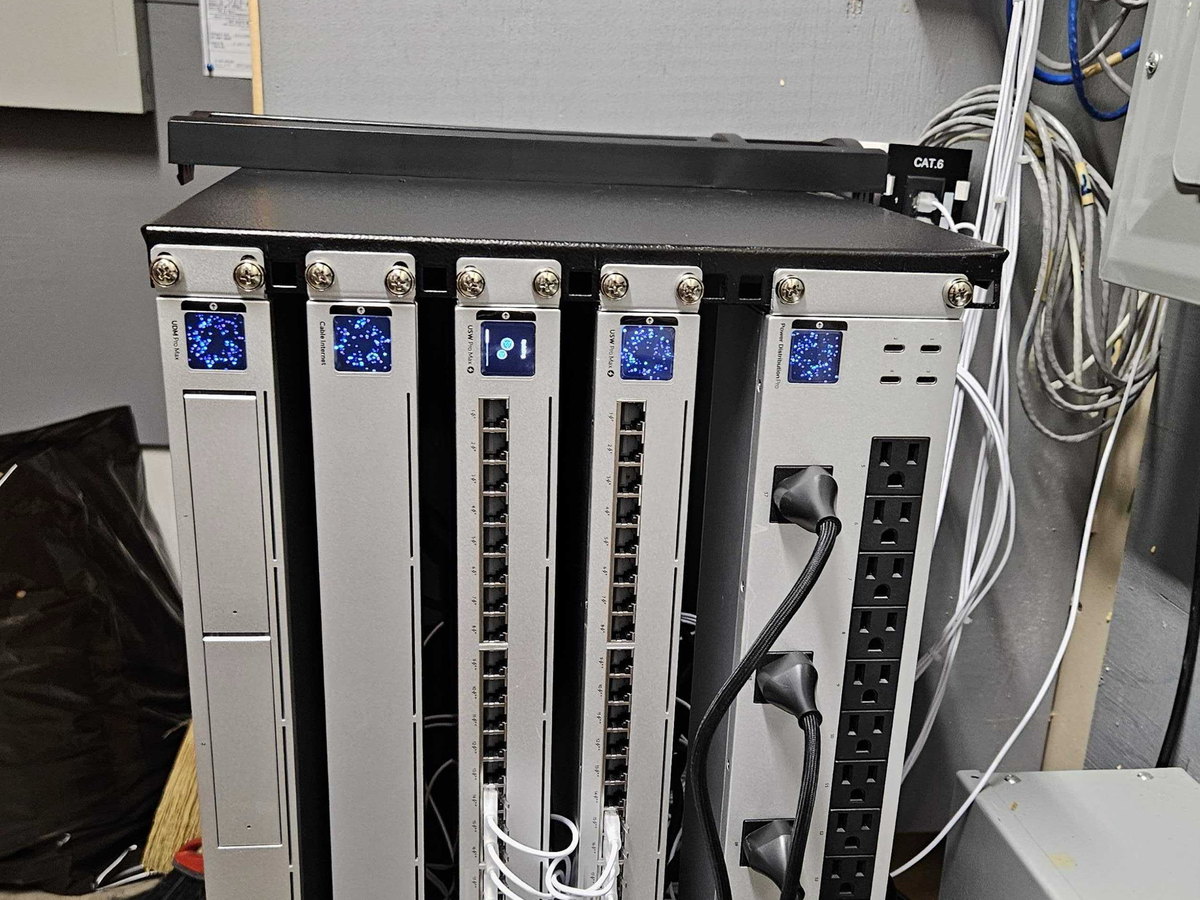 A small equipment rack on one of our own installations, holding a gateway, two power over ethernet switches and a rack power distribution unit, with Cat 6 patch cables dressed down into a punch down panel above.