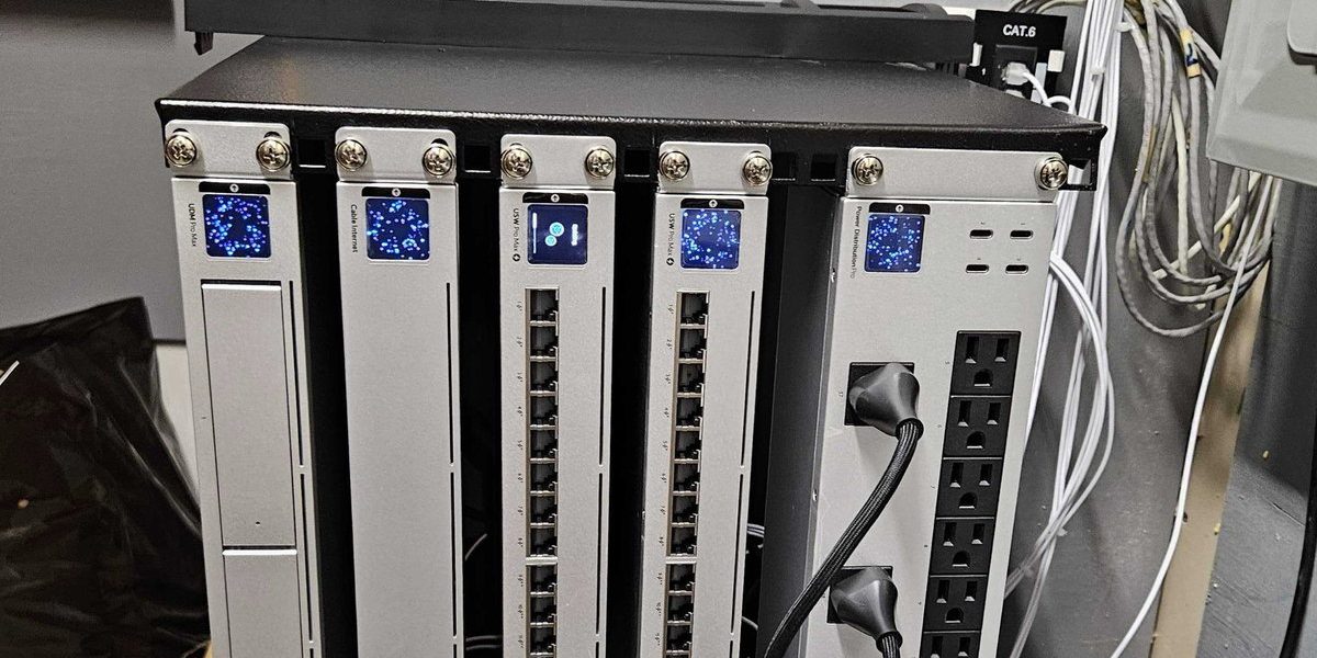Front of a wall mounted UniFi equipment rack installed by Express IT: a gateway, two switches with status screens lit, and a rack power distribution unit, beneath a labeled Cat 6 keystone.