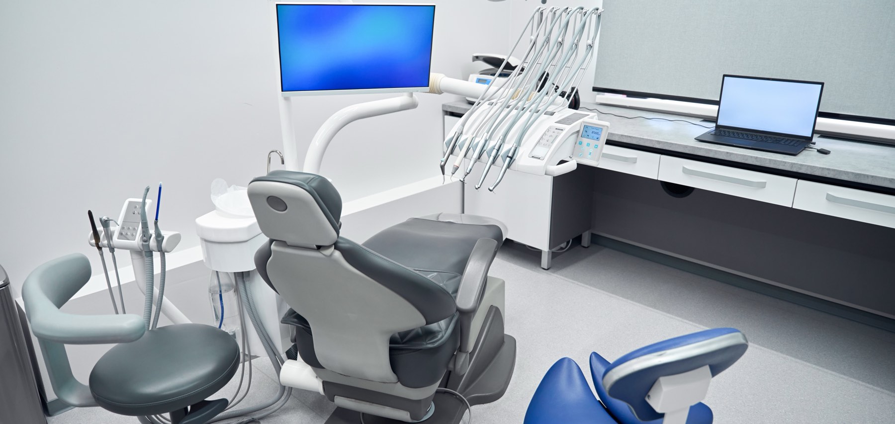 Modern dental operatory with chair, monitor and laptop