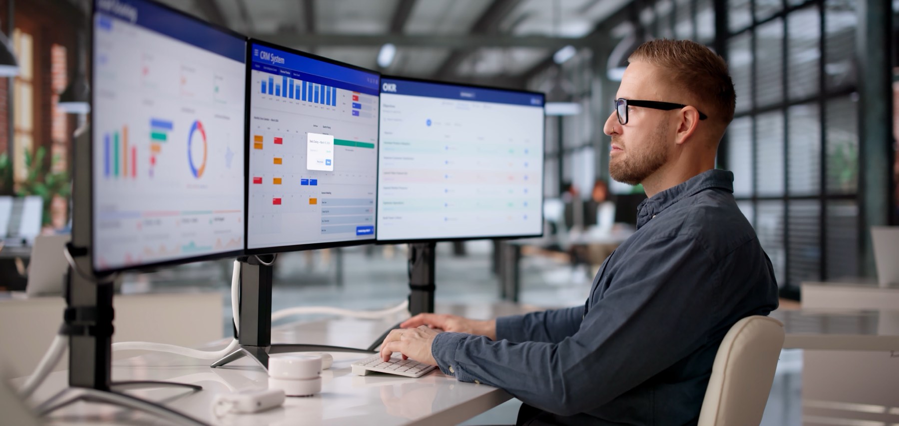 Financial professional working across three monitors of market dashboards in a modern office