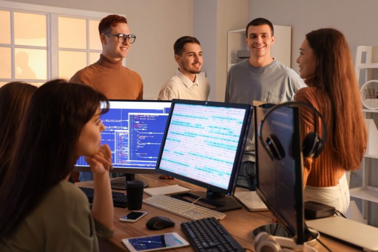 Startup team talking around monitors filled with code