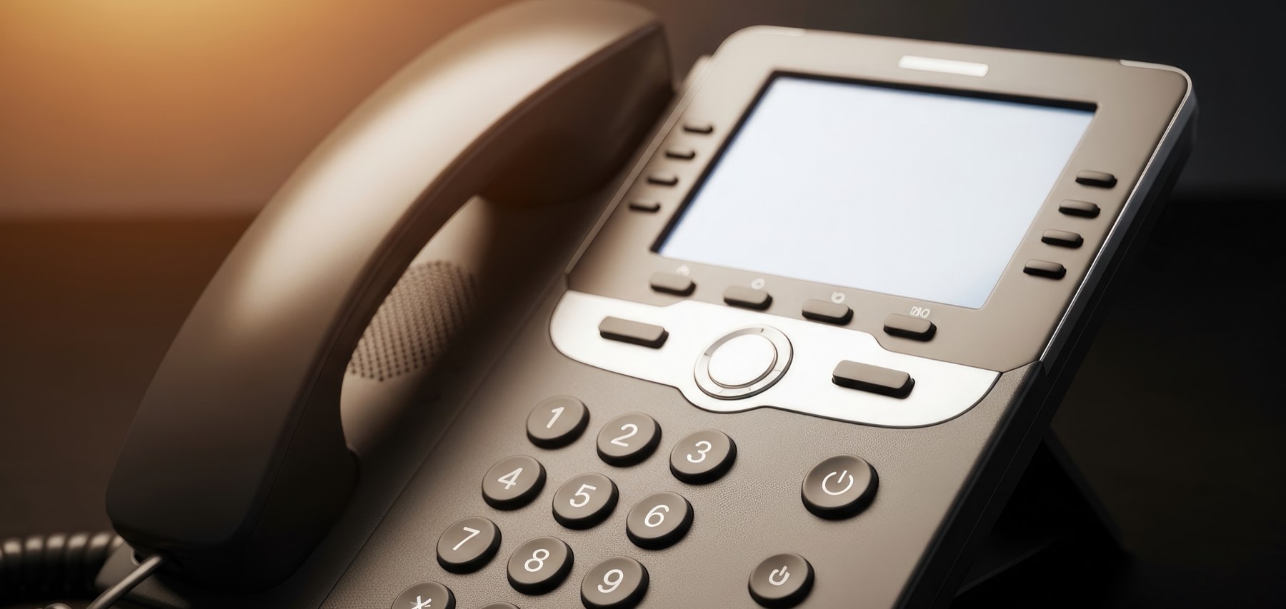 Desk VoIP phone with handset and dial pad in low light